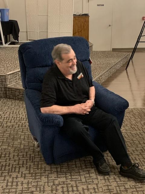"Dr. Neil Sass smiling as he sits in his new rocking chair."