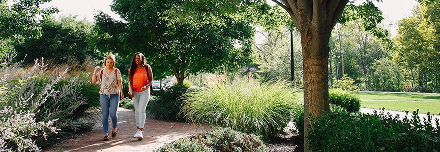 Two students walk through green campus