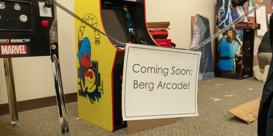 A sign that says "Coming Soon: Berg Arcade!" with several arcade cabinets actively being built in the background.