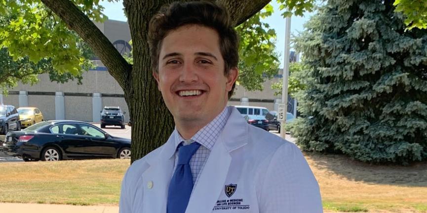 Caleb Gerber in his medical coat posing for photograph