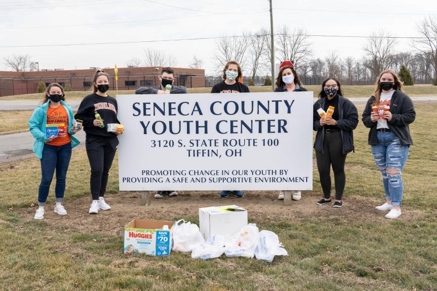 Students stand, masked, with the SYYC sign