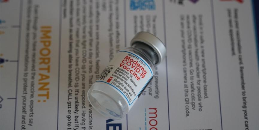 Vial of Moderna vaccine laying on top of information sheet