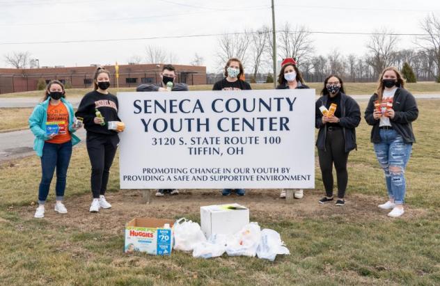 Students stand, masked, with the SYYC sign