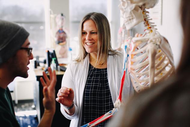 Teacher in lab coat next to skeleton