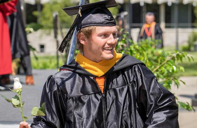student with flower in commencement robe