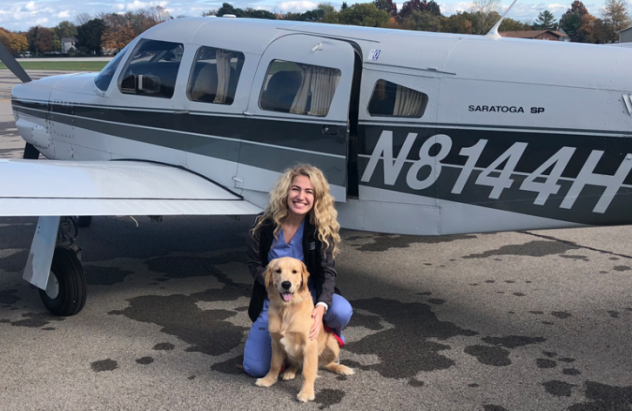 Andrea Russell pictured with dog in front of plane