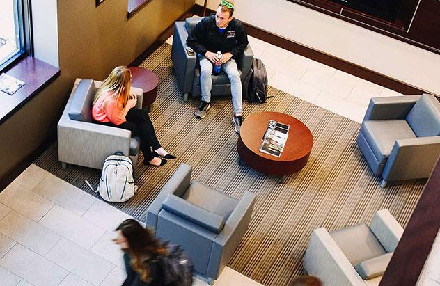 Four students walking in Adams Hall lobby, picture taken from second floor down