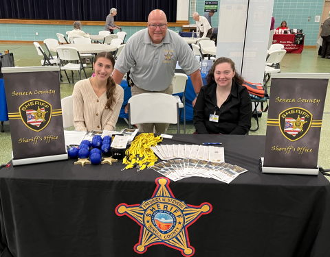 Darian (left) offering resources at the Seneca Country Sheriff's Office's booth at a community event